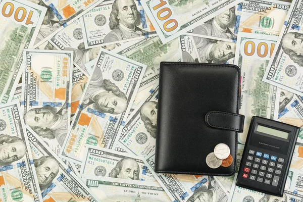 Carteira, moedas, calculadora no fundo de notas de dólar — Fotografia de Stock