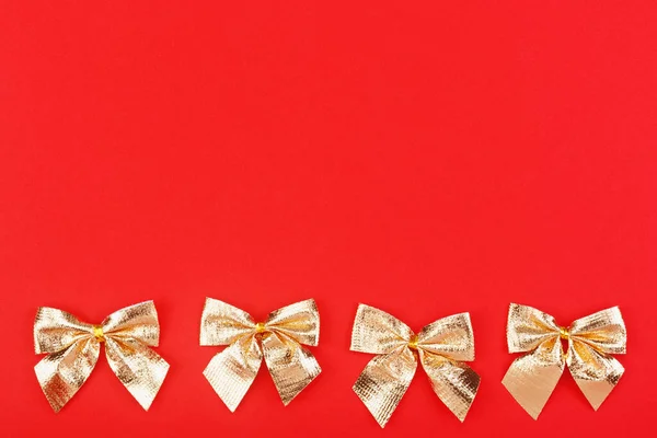 Golden holiday bows on a red background. — Stock Photo, Image