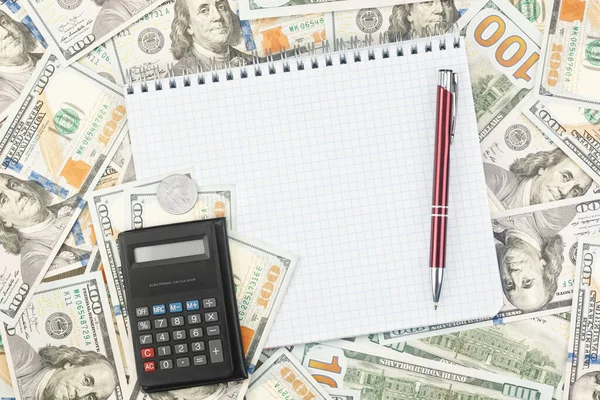 Note book with pen, coin and calculator on the background of dollar bills — Stock Photo, Image