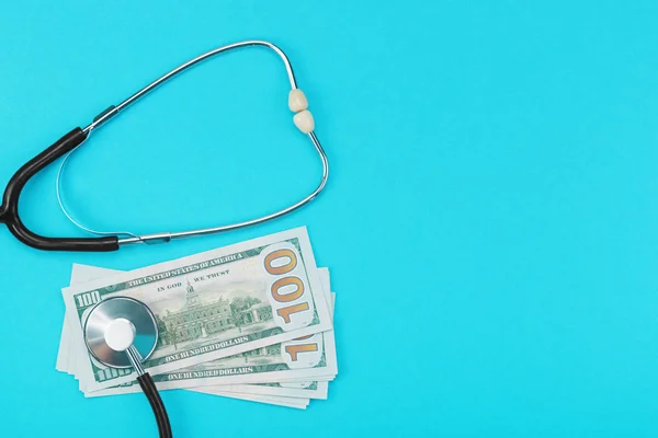 Stethoscope and dollar bills on blue background. — Stock Photo, Image