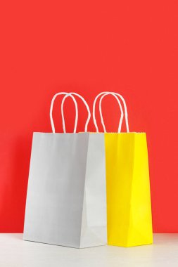 Sarı ve gri alışveriş mi yoksa kırmızı arka plana karşı ahşap masadaki hediye çantaları mı?