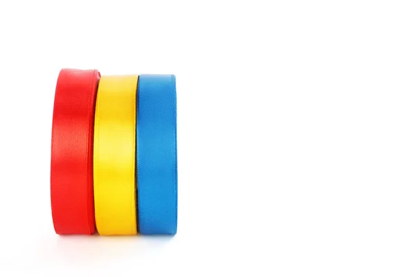 Fitas de cetim brilhantes coloridas em rolos em um fundo branco — Fotografia de Stock