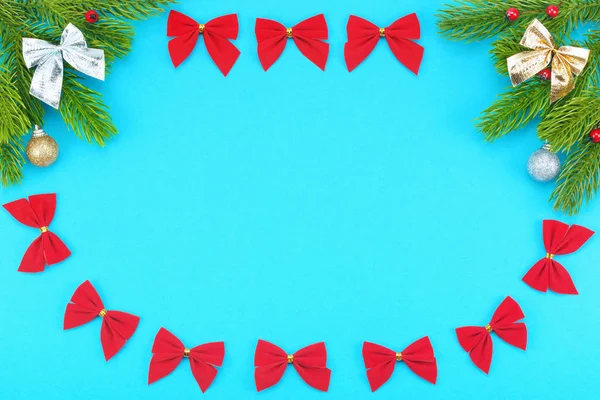 Christmas border with branches of spruce, holidays bows, christmas toys on a blue background — Stock Photo, Image