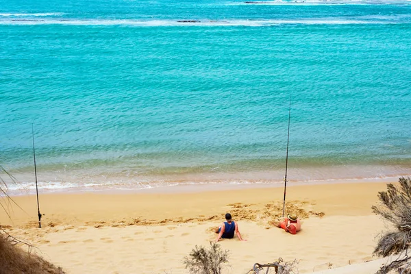 Twee man ontspannen op een strand met hengels. — Stockfoto