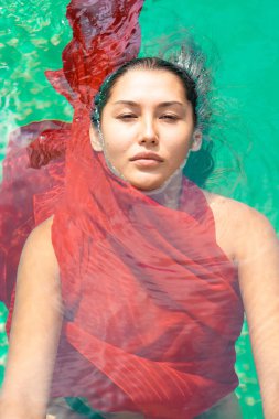 Kırmızı elbiseyle yüzen çekici bayan.