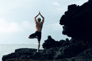 Atletizm sporcusu dışarıda yoga yapıyor.