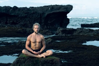 Atletizm sporcusu dışarıda yoga yapıyor.