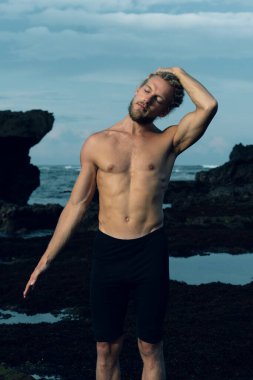 Atletizm sporcusu dışarıda yoga yapıyor.