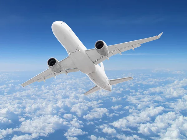 large white passenger plane flies high above the clouds