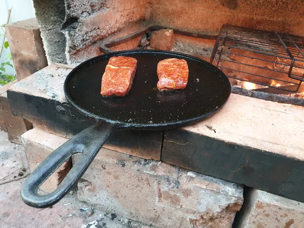 肉のジューシーな切り身は鋳鉄製の鍋で焼かれますバーベキューオーブンで石炭を燃焼 — ストック写真