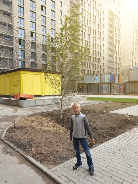 幸せな少年は現代の住宅団地ビジネスクラスの彼の新しい家の庭に立つ — ストック写真