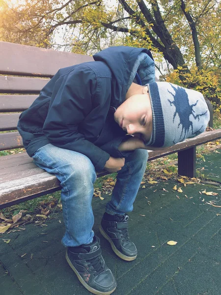 悲しい少年がベンチに座って屋外で — ストック写真