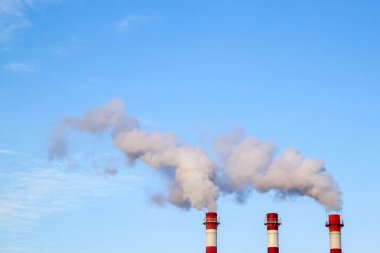 Bir termik santralde sigara içmek, mavi gökyüzündeki atmosfere kirli hava yayar.