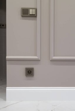 İç kısmının bir kısmı, süpürgeliğin ve mermer zeminin üstündeki kahverengi duvarda bir elektrik prizi var.