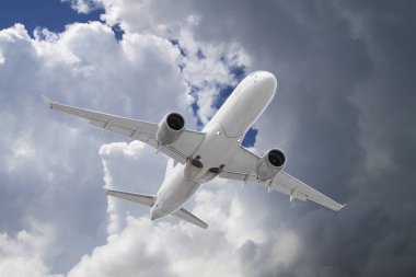 Beyaz yolcu uçağı mavi gökyüzü arka planında güzel uğursuz bulutların zemininde uçar.
