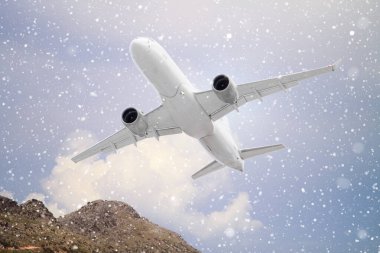 Beyaz yolcu uçağı, sonbaharda mavi gökyüzü arka planında beyaz bulutlarla düşen karların arasından uçar. Uçakla, dağlarla ve yazları beyaz bulutlu mavi gökyüzüyle manzara. Avrupa 'da iş seyahati. 