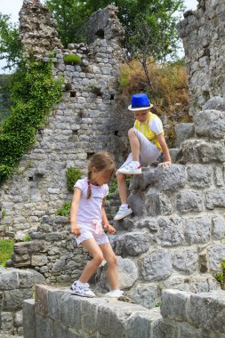 Oğlan ve kız eski bir binanın kalıntılarına tırmanıyor.