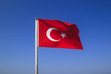 Turkish flag waving on the flagpole in the wind against the blue sky clipart