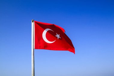 Türk bayrağı mavi gökyüzüne karşı rüzgarda dalgalanırken