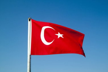 Türk bayrağı mavi gökyüzüne karşı rüzgarda dalgalanırken