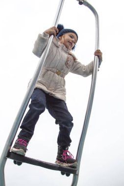 Sonbahar elbiseli kız modern metal atlıkarıncada döner ve denge sağlar.