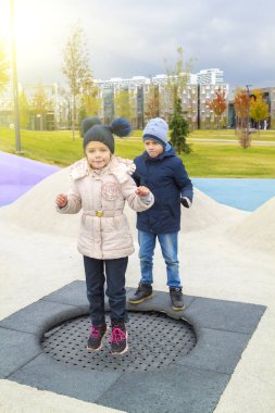 Mutlu kız trambolinde zıplıyor ve huysuz oğlan kızgın ve modern oyun parkına atlamak için sırasını bekleyemiyor.