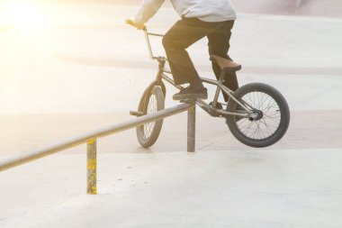 Kaykay parkında bmx sürücüsü. Rampada kayarak kayma numaraları deniyor.