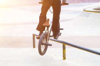 Kaykay parkında bmx sürücüsü. Rampada kayarak kayma numaraları deniyor.