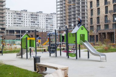 Sevimli çocuk yeni modern ekipmanlara tırmanıyor bahçedeki çocuk parkında konut kompleksinde inşaat işletme sınıfı altında.