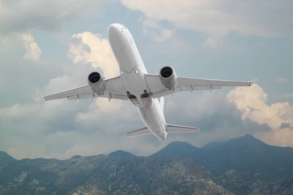 白い旅客機は青い空の背景に白い雲を持つ山に対して離陸する 夏には白い雲と飛行機 海と青空と風景 ヨーロッパでのビジネス旅行 — ストック写真