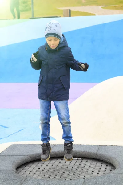 Menino Roupas Quentes Pulando Trampolim Parque Infantil Moderno Livre — Fotografia de Stock