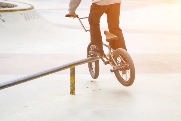 bmx rider in skate park practicing tricks sliding on frame of bike on ramp