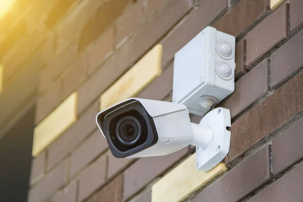 Closed-circuit television camera mounted on brick wall. CCTV security camera outdoors.