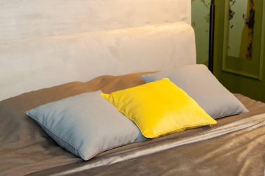 Dekoratif yastıklı kahverengi bir battaniye, yatak odasındaki kumaştan bir yatak başlığı.