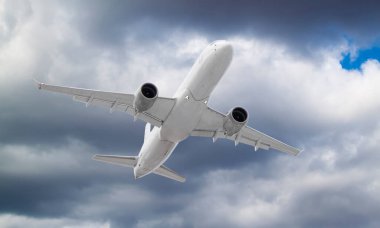 Fırtınalı gri ve beyaz bulutların arasında uçan uçak