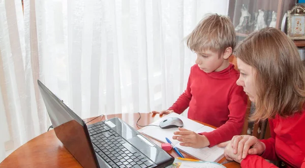 Distance learning, remote online education at home. Child studying from home with help of mother taking remote class because of social distance. Mother helping her son with his homework or e-learning from home during Covid-19 pandemic lockdown