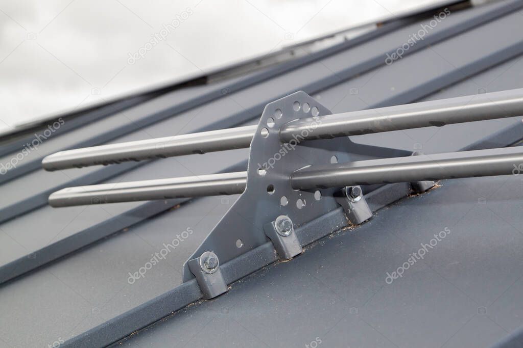 Close up view of fastening metal snow retainer with screws to the roof