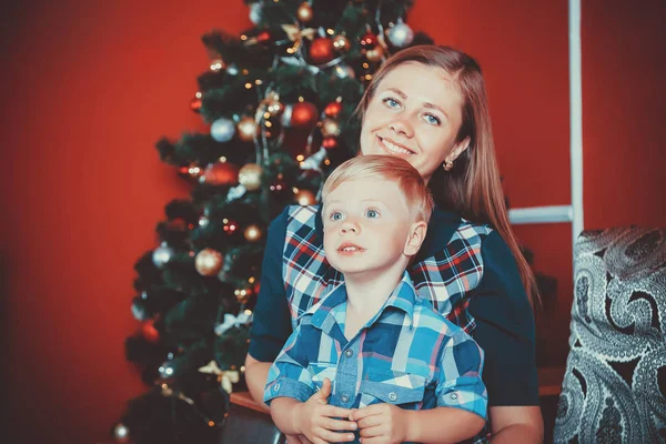 Gyönyörű portréja boldog anya és fia, a háttérben a karácsonyfa — Stock Fotó