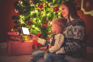 Anne ve oğlu Noel ağacının yanında oturan 