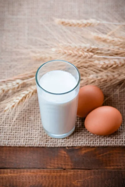 Bicchiere di latte, uova e frumento in tavola — Foto Stock