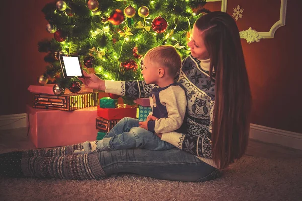 Matka a syn sedí u vánočního stromu — Stock fotografie