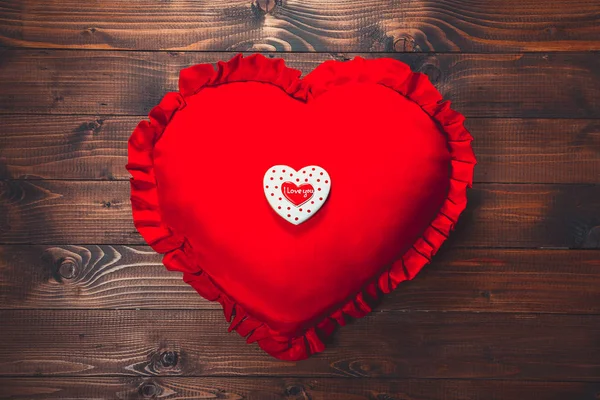 Heart-shaped biscuit on red pillow — Stock Photo, Image