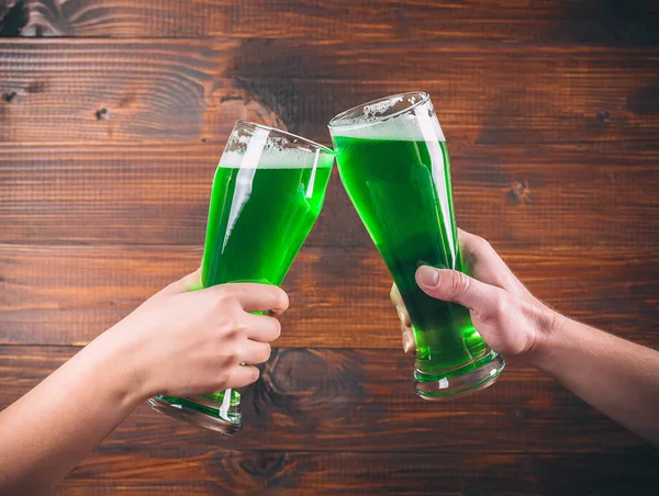 Mugs in hands with green beer — Stock Photo, Image