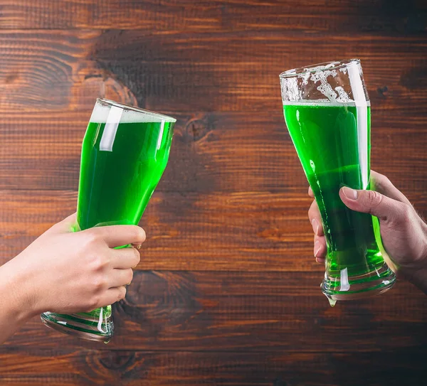 Mugs in hands with green beer — Stock Photo, Image