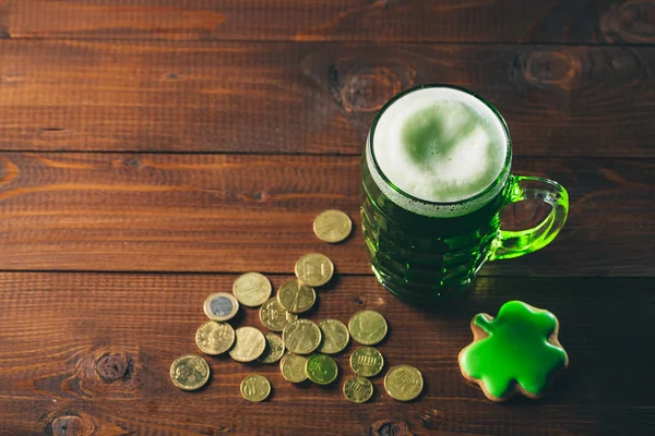 Glass of green beer, coins and gingerbread — Stock Photo, Image