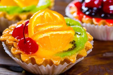 Lezzetli meyve kek çilek, kiraz, kuş üzümü ve ahududu kahverengi ahşap zemin üzerine. Güzel, keyifli ve sağlıklı tatlılar