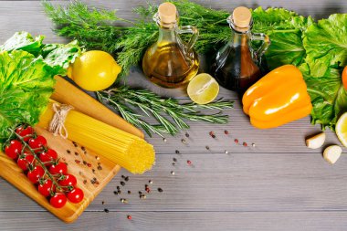 Spagetti, cherry domates, zeytin yağı, bitki ve baharat eski gri ahşap arka plan üzerinde. Sağlıklı gıdalar için ayarlayın. Salata için malzemeler