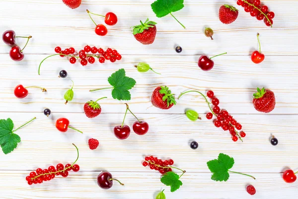 Bunte köstliche frische Früchte Erdbeeren, Kirschen, Johannisbeeren und Himbeeren auf weißem Holzgrund. schöne, köstliche und gesunde Desserts — Stockfoto