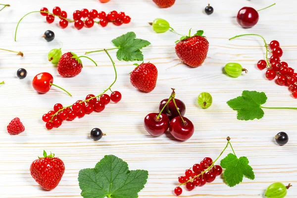 Färgglada läckra färsk frukt jordgubbar, körsbär, vinbär och hallon på vit trä bakgrund. Vackra, härliga och friska desserter — Stockfoto
