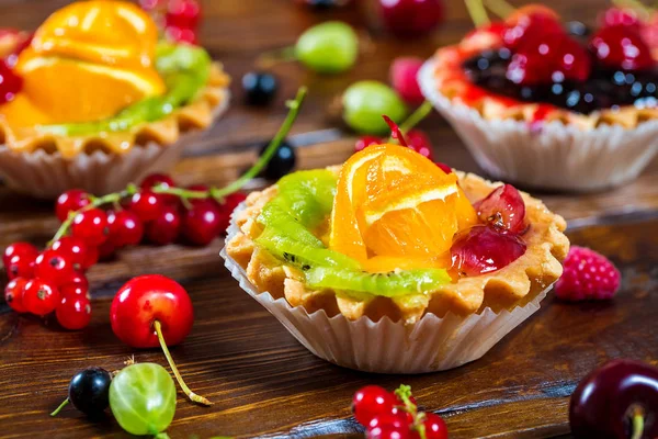 Delicioso bolo de frutas em fundo de madeira marrom com morangos, cerejas, groselhas e framboesas. Sobremesas bonitas, deliciosas e saudáveis — Fotografia de Stock